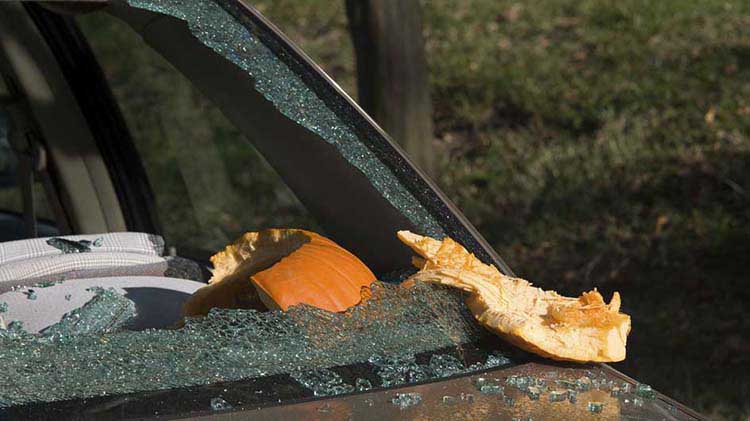 A shattered car windshield caused by a thrown or falling pumpkin — a reminder to handle pumpkins carefully and keep them away from vehicles.